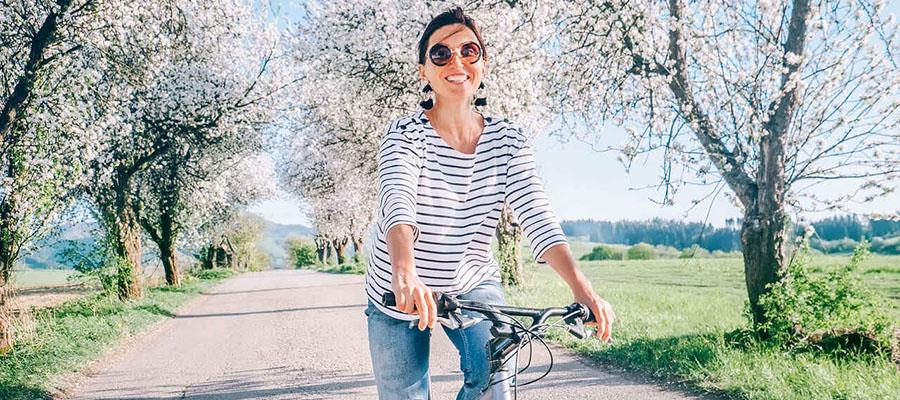 Woman riding her bike through a path with blooming trees