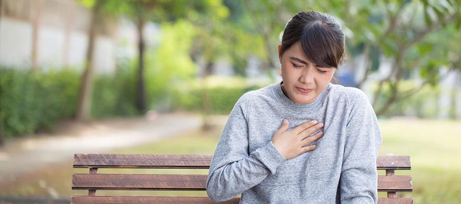 Woman holding chest, having heartburn