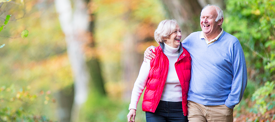 Grey haired man and woman walking together in woods