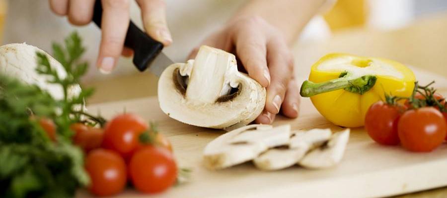 Person cutting vegetables on cutting board in kitchen