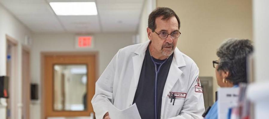Doctor leaning in to talk to nurse in hospital hallway