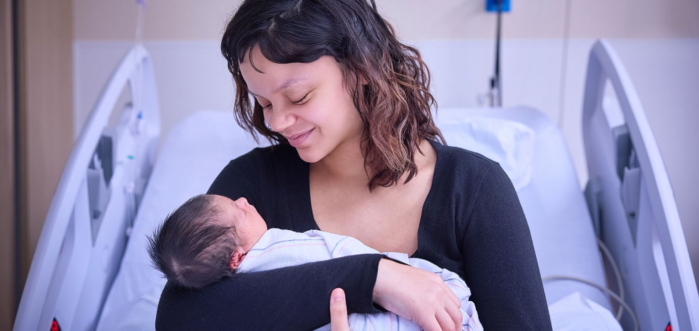 Mom holding newborn child in hospital bed