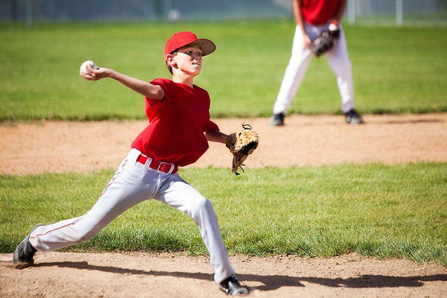 Little League baseball player pitching at game