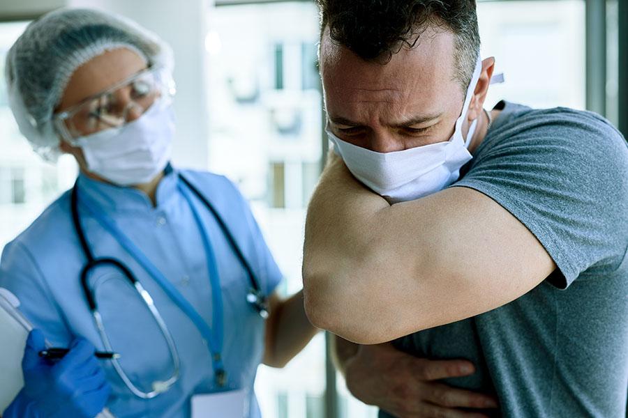 man wearing mask coughing into shoulder