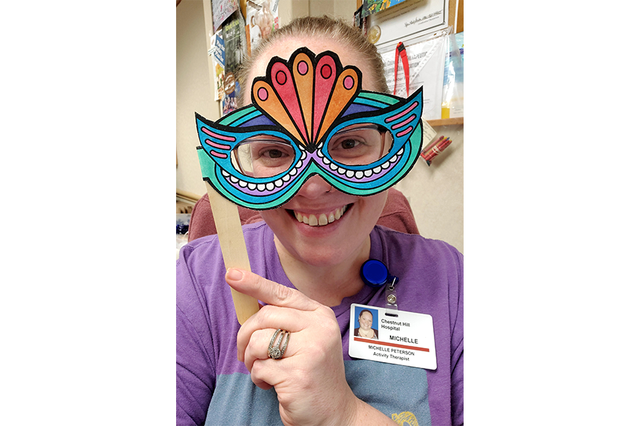 Certified Recreation Therapist Michelle Peterson with one of the masks she and her patients made during the Mardi Gras celebration.