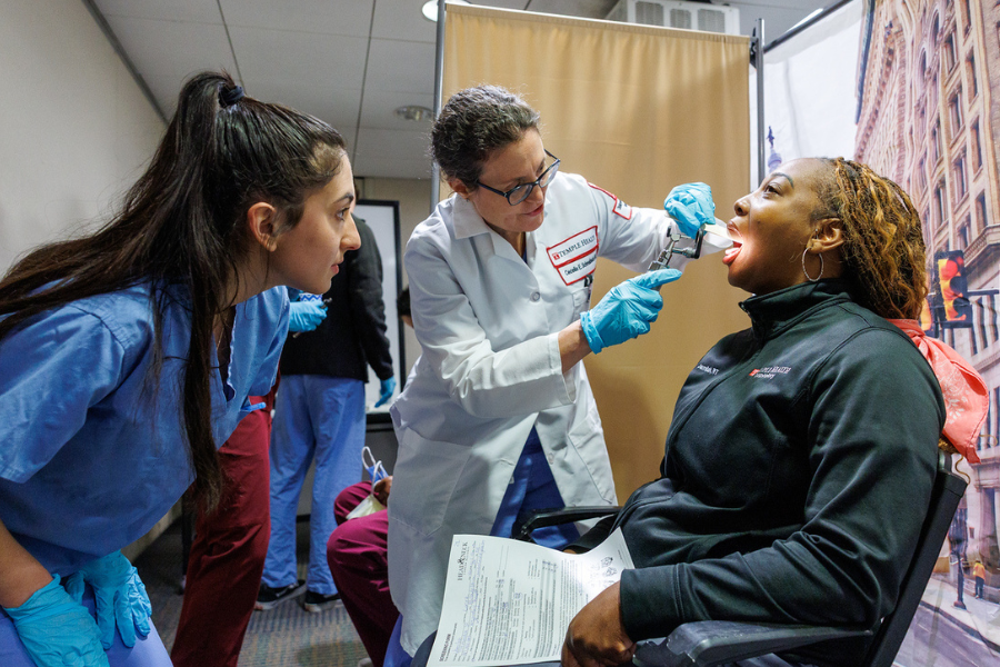 Dr. Cecelia Schmalbach (center) performs a screening at the Head and Neck Cancer event.