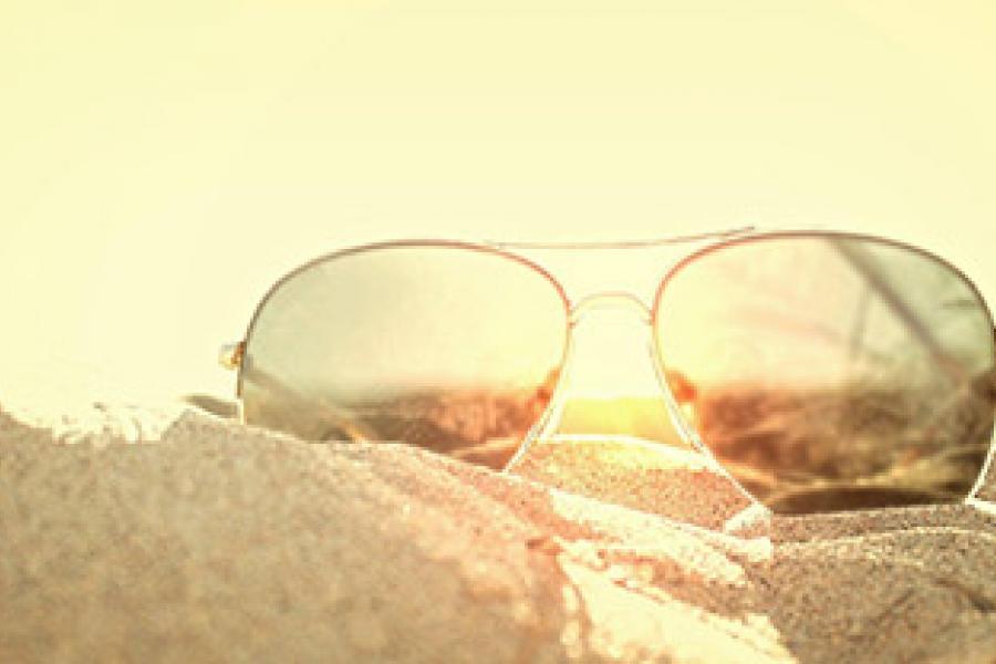 Pair of sunglasses laying on top of sand
