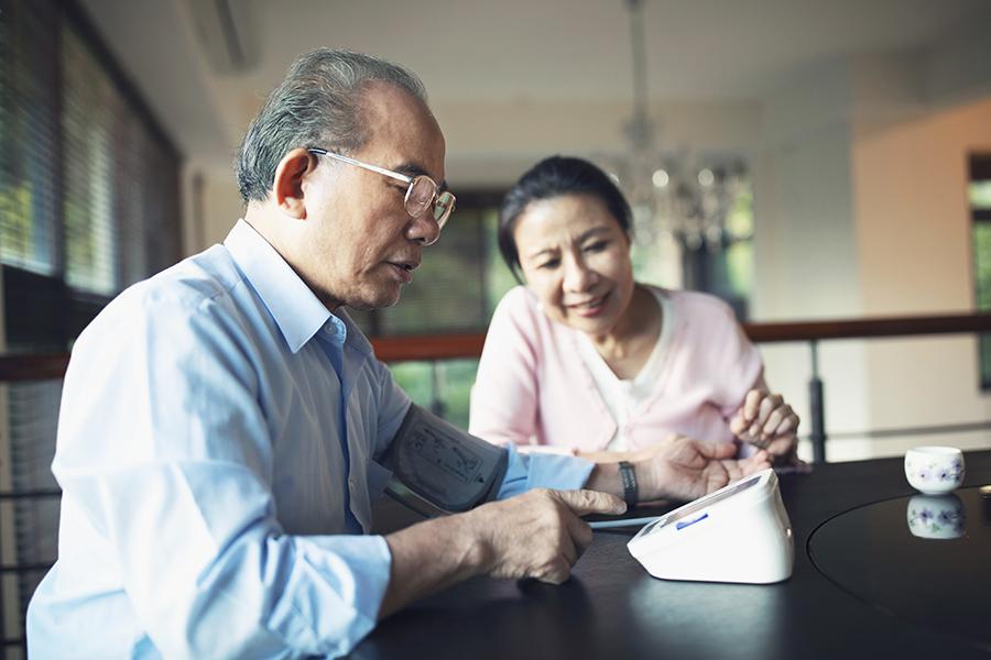 Older man checking his blood pressure at home