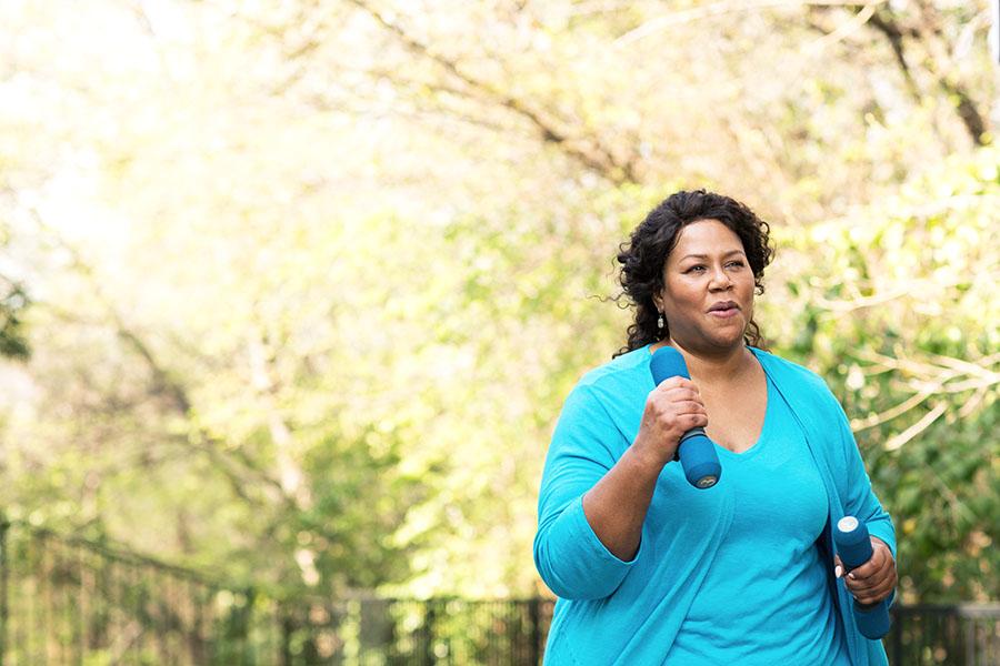 Woman walking outside while holding weights