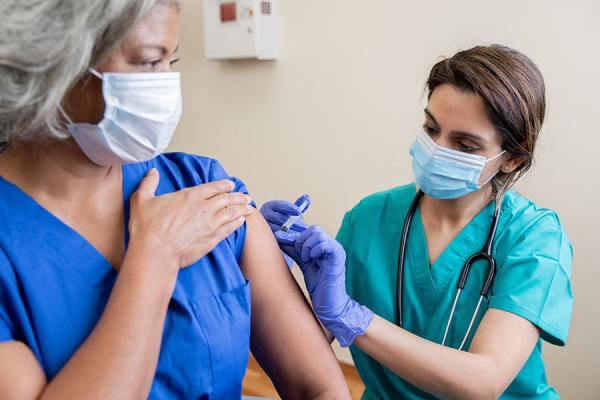 Nurse giving healthcare worker COVID vaccine