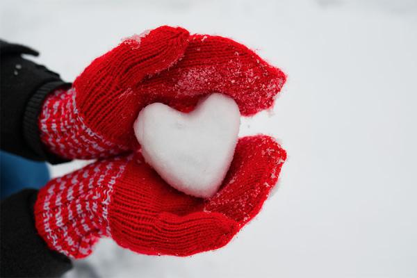 Heart-shaped snowball in gloved hand