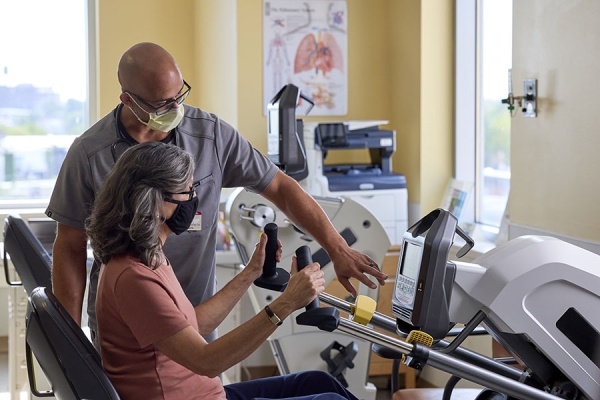 Rick Medina helping a patient on the exercise bike