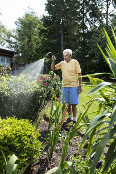 Jeanes patient, Albert, watering flowers in his garden