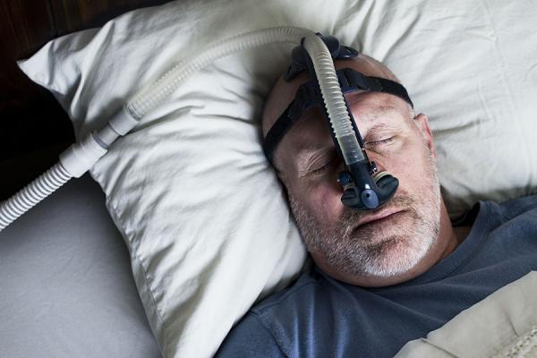 Man sleeping in bed using CPAP machine