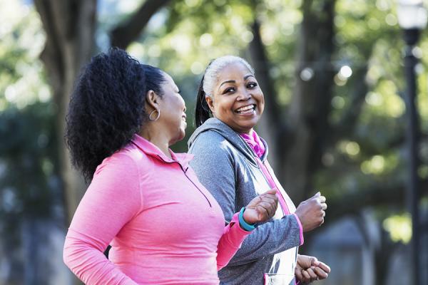 Two happy women walking and talking in the park